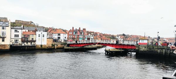 Buildings by river against sky in city, whitby sea side, bridge 