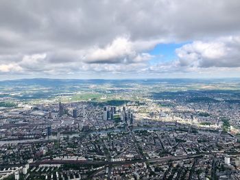 Aerial view of city buildings against cloudy sky