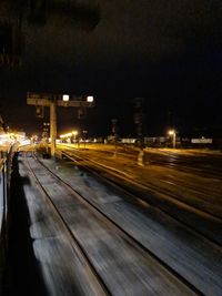 Illuminated railroad tracks in city at night