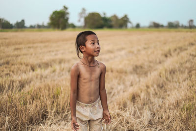 Portrait of shirtless boy standing on field
