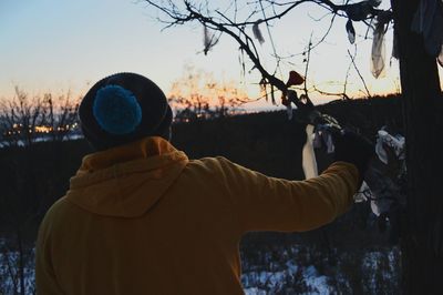 Close-up of man standing by bare tree against sky