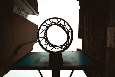 Directly below shot of basketball hoop amidst buildings against clear sky