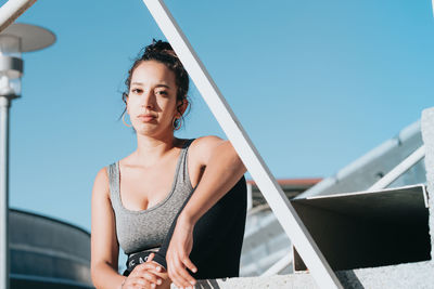 Portrait of young woman standing against sky