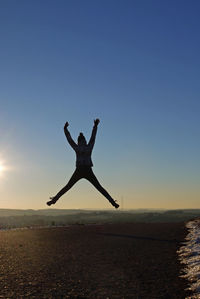 Man jumping at beach against sky