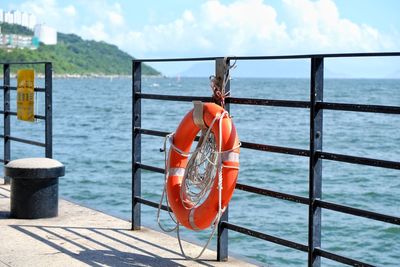 Close-up of railing by sea against sky