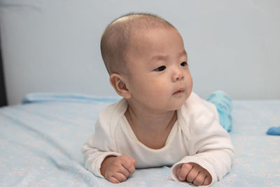 Portrait of cute baby girl lying on bed