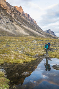 Man standing on rock by mountain against sky