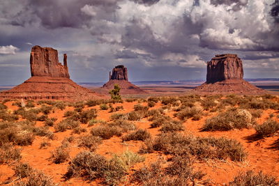 Scenic view of monument valley against dark clouds