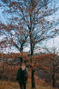 Rear view of person standing on tree during autumn