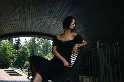 A pretty charming middle-aged woman in a black dress and sunglasses strolls through the city park