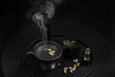 Smoking frankincense, cross, holy water, on a black background. conceptual image