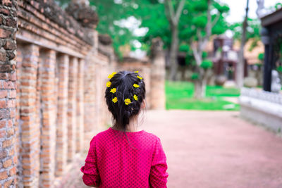 Rear view of woman standing by flowering plant