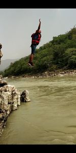 Full length of man jumping in water against sky