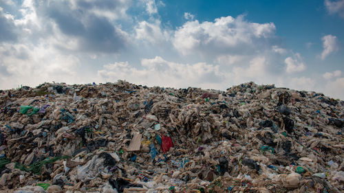 Stack of garbage on rock against sky