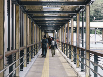 Rear view of people walking in footbridge