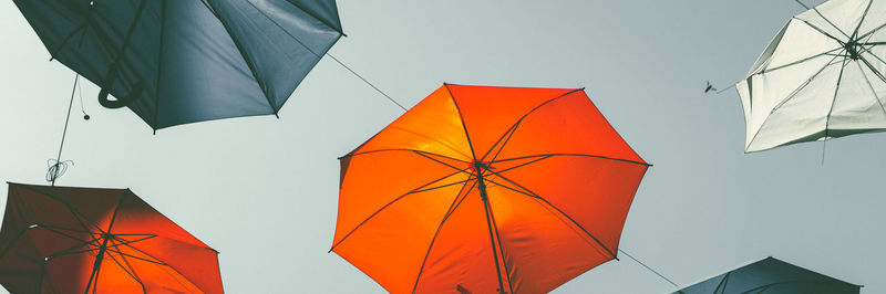 Low angle view of umbrellas hanging against sky