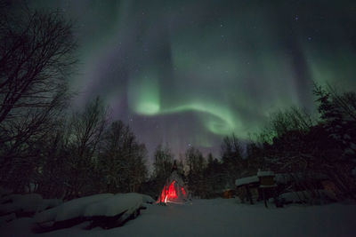 Low angle view of aurora borealis over snow covered field