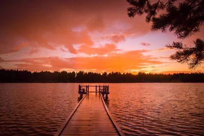 View of pier over calm lake at sunset