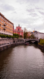 Arch bridge over river against buildings in city