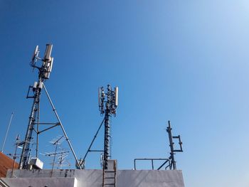 Low angle view of communications tower against clear blue sky