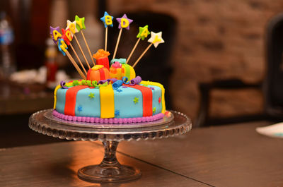 Close-up of birthday cake on stand over table
