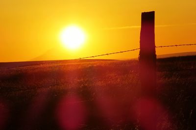 Scenic view of field against orange sky