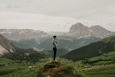 Woman standing on top of the rock overlooking the mountains