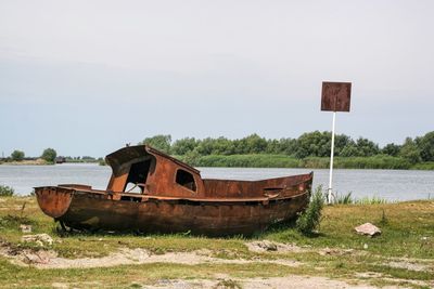 Abandoned boat moored at shore against sky