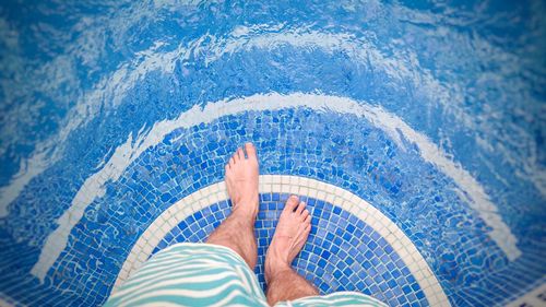 Low section of man standing by swimming pool