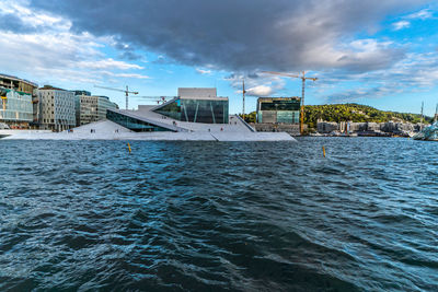 Buildings by sea against sky