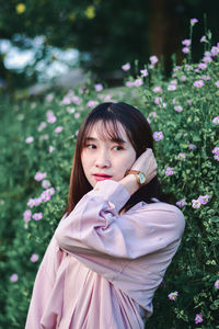 Portrait of young woman standing against plants