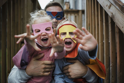 Portrait of children with father in superhero costumes