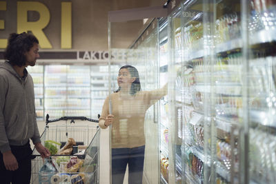 Couple standing in supermarket and talking while shopping