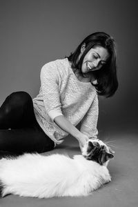 Smiling woman with cat against gray background