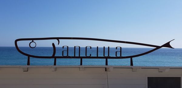 Metallic structure in sea against clear blue sky