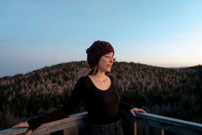 Young woman looking at camera against sky