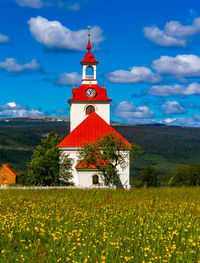 Traditional windmill on field by building against sky