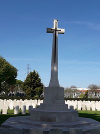 Cross in cemetery against sky