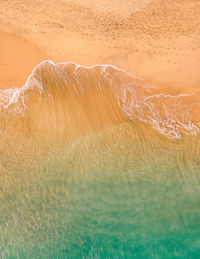 Aerial view of atlantic ocean coast with crystal clear turquoise water, waves rolling into the shore