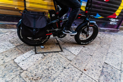 Low section of man riding bicycle on footpath