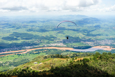 Scenic view of landscape and paragliding   against sky