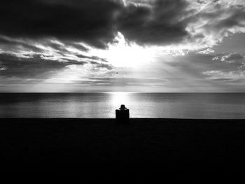 Silhouette of man looking at sea against sky