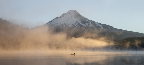 Panoramic view of boat in lake by snowcapped mountain against sky