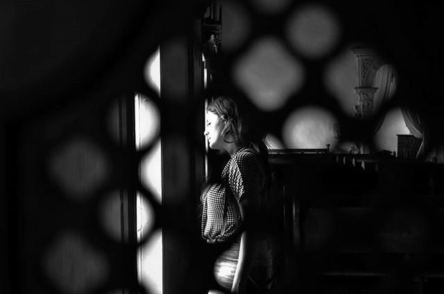 indoors, night, illuminated, built structure, low angle view, focus on foreground, architecture, selective focus, hanging, one person, lighting equipment, window, religion, railing, close-up, place of worship, spirituality, building exterior