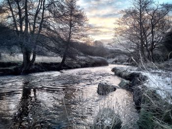 Scenic view of river against cloudy sky