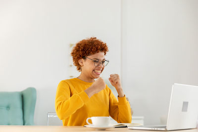 Young woman using laptop while sitting on table