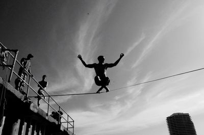 Low angle view of silhouette man jumping against sky