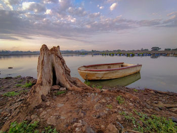 Abandoned boat moored on beach against sky during sunset