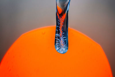 Close-up of water drops on glass against orange background