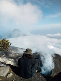 Rear view of man sitting on mountain